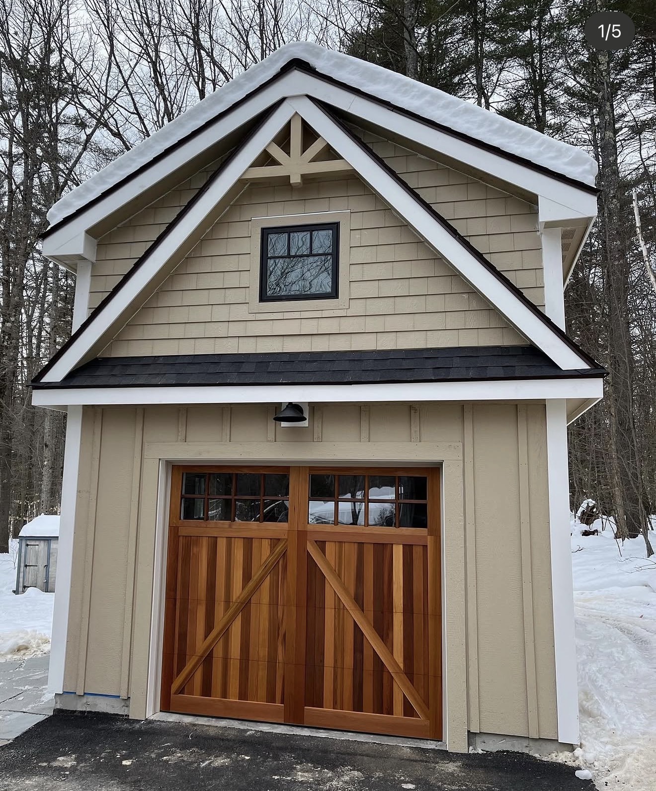 Cream shingle-style custom garage addition with cedar carriage door in winter, New Hampshire