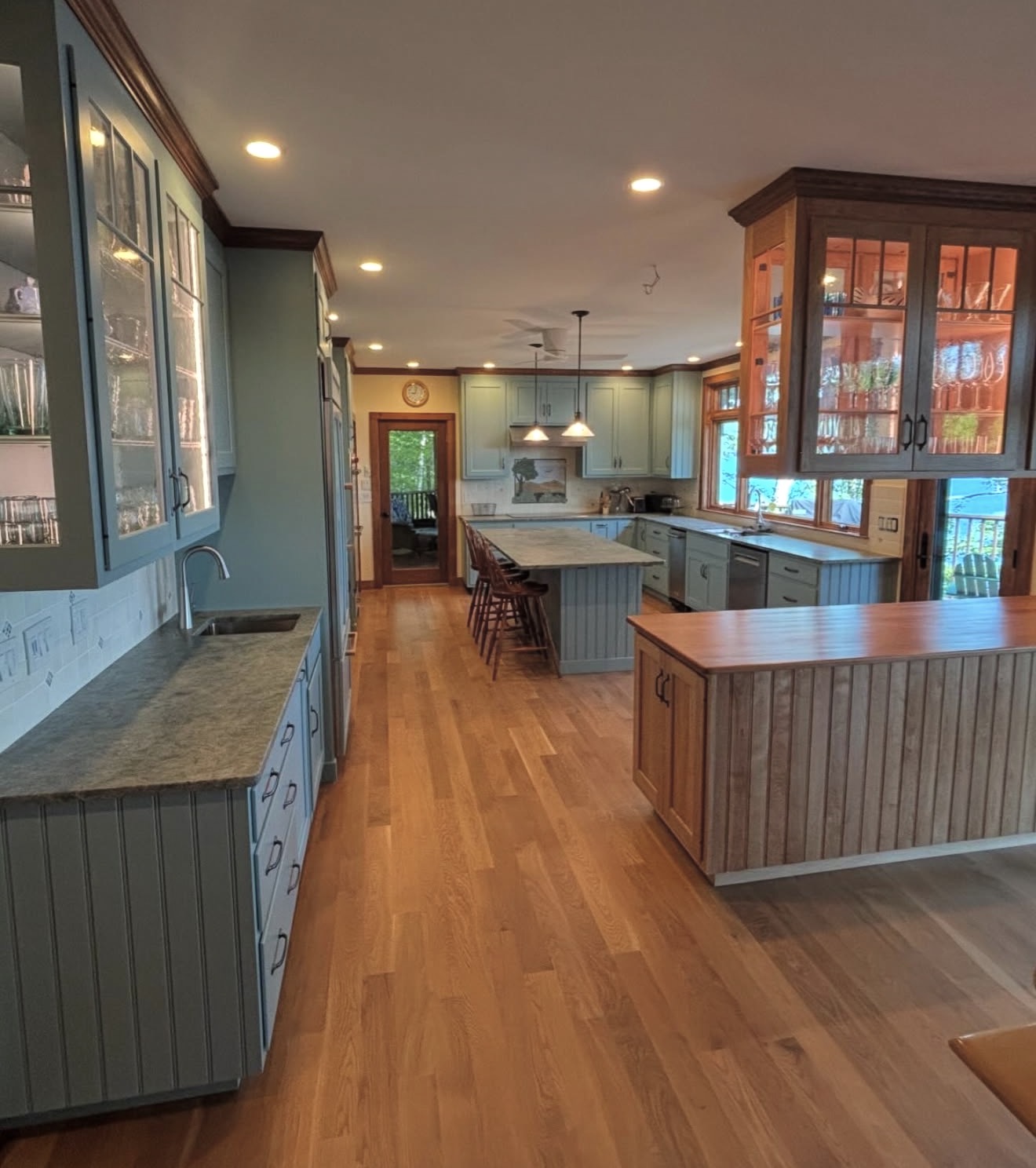 Lakeside kitchen remodel with beadboard island, glass-front display cabinets, and white oak floors in the NH Lakes Region